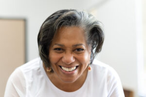 A woman wearing a white shirt smiles at the camera.