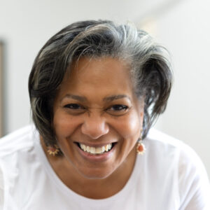 A woman wearing a white shirt smiles at the camera.