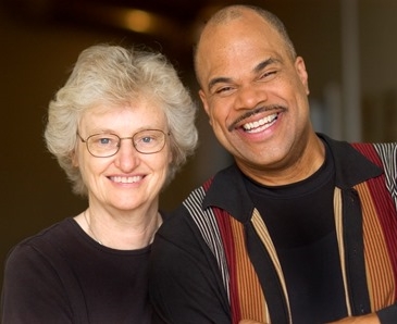 Anita is a white female wearing a black shirt and T. Mychael is a black male wearing a striped shirt.