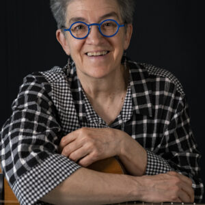 portrait of a woman holding a guitar and smiling directly at the camera