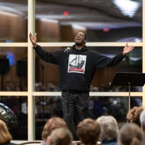 Frank Sentwali with his arms out performing for a crowd.