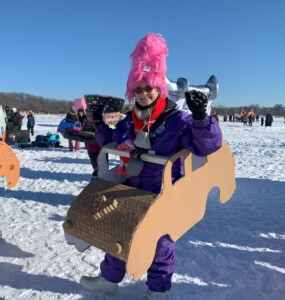 Jan is a white female wearing a pink hat and purple snowsuit.