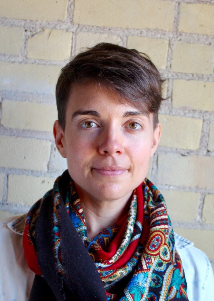 Glenda is a white female wearing a denim shirt with multicolored scarf.