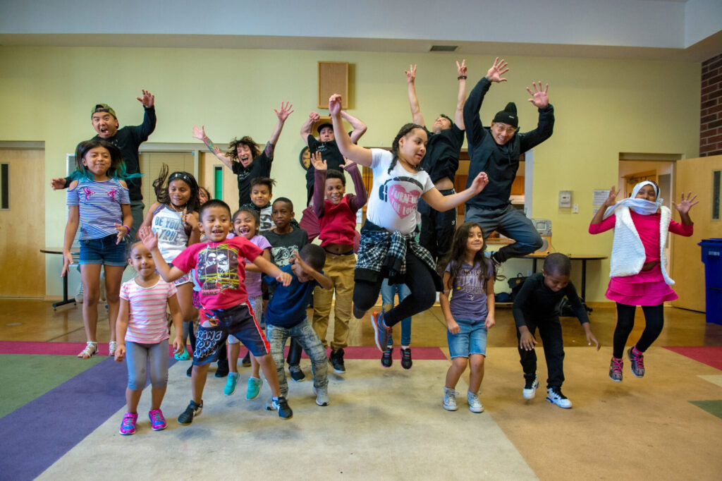 A bunch of kids jump up and cheer in the classroom.