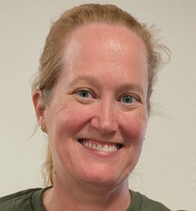 Smiling, Ann Dayton in front of a white wall.