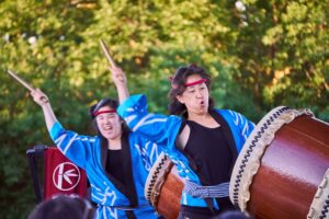 Two women in traditional dress play Taiko drums.