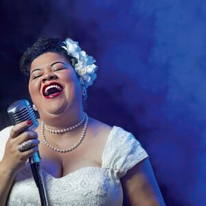 Thomasina Petrus as Billie Holliday singing into a mic.