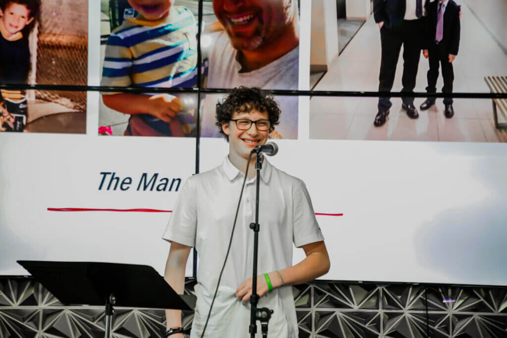 Sam smiling while performing at the 2026 Youth Spoken Word Showcase.