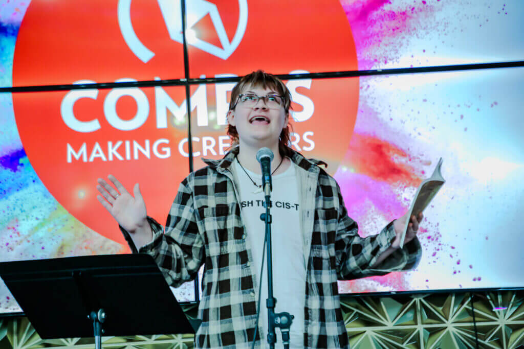 Know holding a book with an expressive stance while performing at the 2026 Youth Spoken Word Showcase.